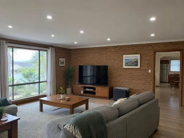 Living room with recessed ceiling downlights, brick feature wall and large window in Tumbi Umbi